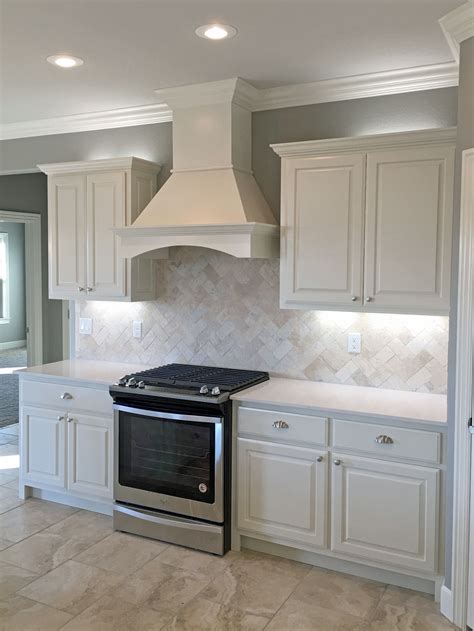 White kitchen with satin nickel fixtures, pendant lights, travertine backsplash, white qua ...