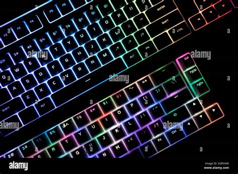 top view detail closeup of two illuminated mechanical gaming RGB keyboard on black desk next to ...