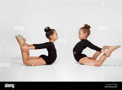 two young beautiful gymnast girls in black sportswear performs gymnastic poses Stock Photo - Alamy