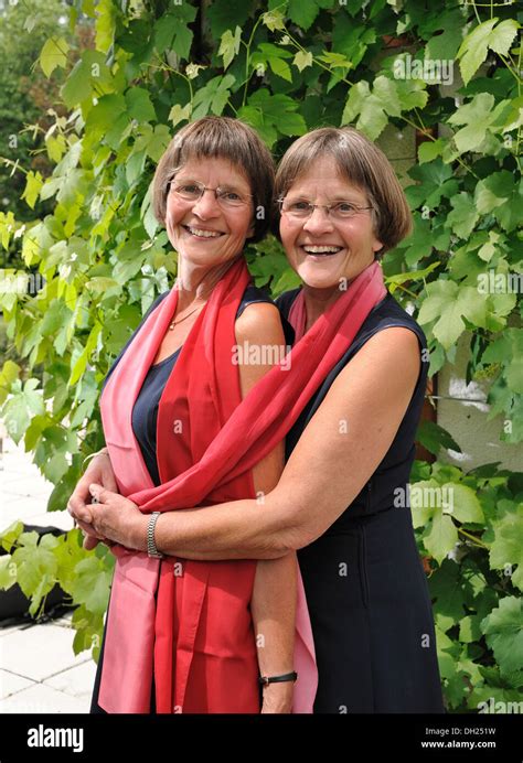 Zwei rüstige Zwillingsschwestern gekleidet gleichermaßen und tragen rote Schals Stockfotografie ...