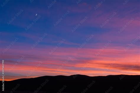 Sunset landscape with moon overlooking mountains in silhouette in Colorado's Rocky Mountain ...