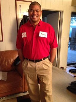 a man in a red shirt and khaki pants standing next to a couch