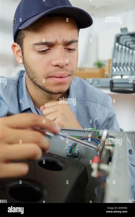 serviceman frowning while trying to test appliance Stock Photo - Alamy