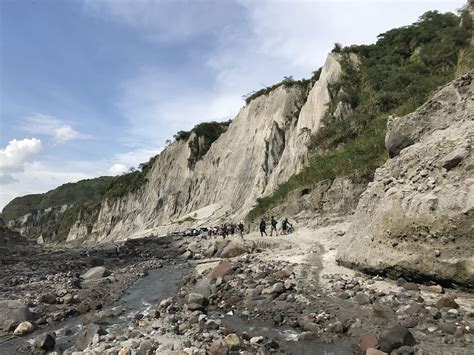 a group of people standing on the side of a cliff next to a river and rocks