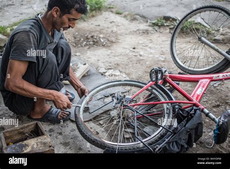 A bicycle repair man fixing a flat tire on a bike on a late afternoon in north India Stock Photo ...