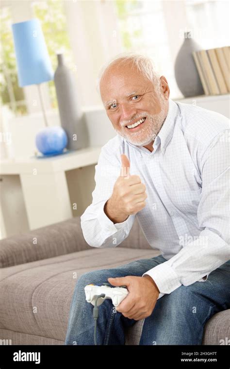 Older man giving thumb up with computer game Stock Photo - Alamy