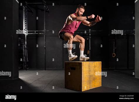 Man in sportwear jumping onto yellow box. Vertical box jumps workout ...