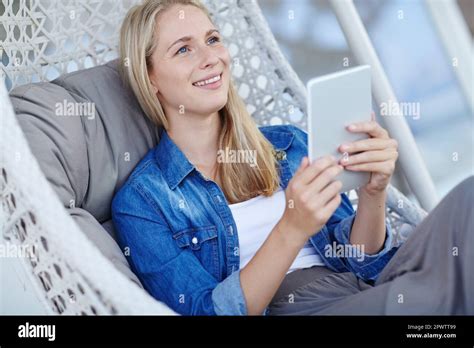Wireless freedom. a young woman using a digital tablet while relaxing in a hanging basket chair ...