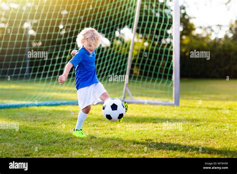 Kids play football on outdoor field. Children score a goal during soccer game. Little boy ...