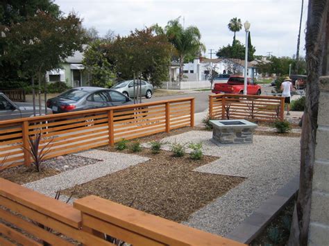 a wooden bench sitting in the middle of a park next to a street with parked cars