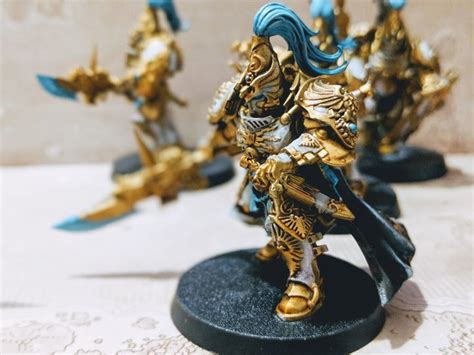 some gold and blue figurines are on a white tablecloth with laces