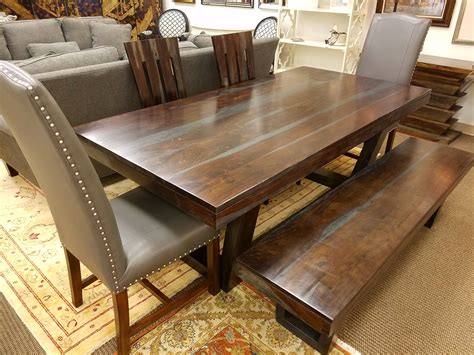 a wooden table and bench in a room with rugs on the floor next to couches