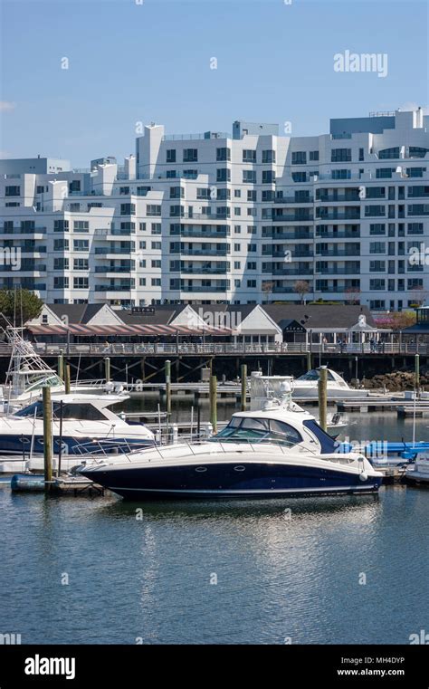 Yachts moored at Marina Bay docks, in front of a waterfront boardwalk, restaurants and ...