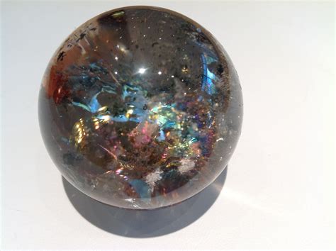 This Smoky quartz sphere has chlorite inclusions and displays an almost "oily" rainbow ...