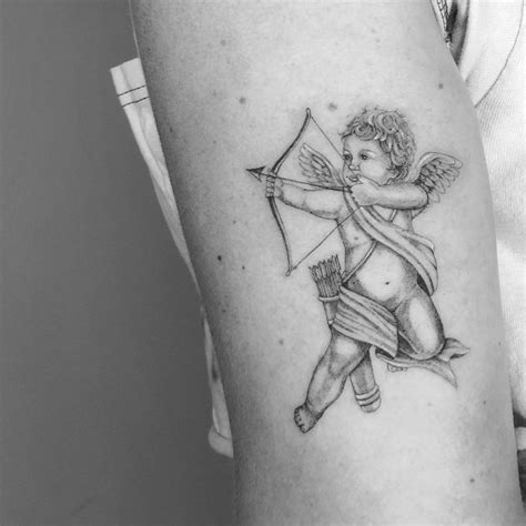 Micro-realistic Cupid tattoo on the upper arm.