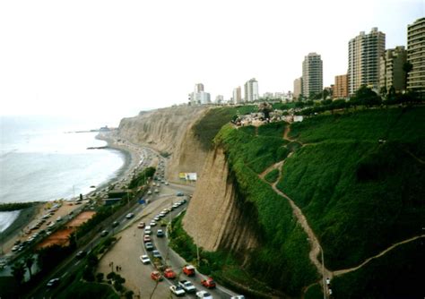 an aerial view of a beach with cars parked on the shore and high rise buildings in the background