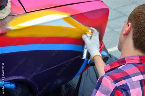 A young red-haired graffiti artist paints a new colorful graffiti on ...