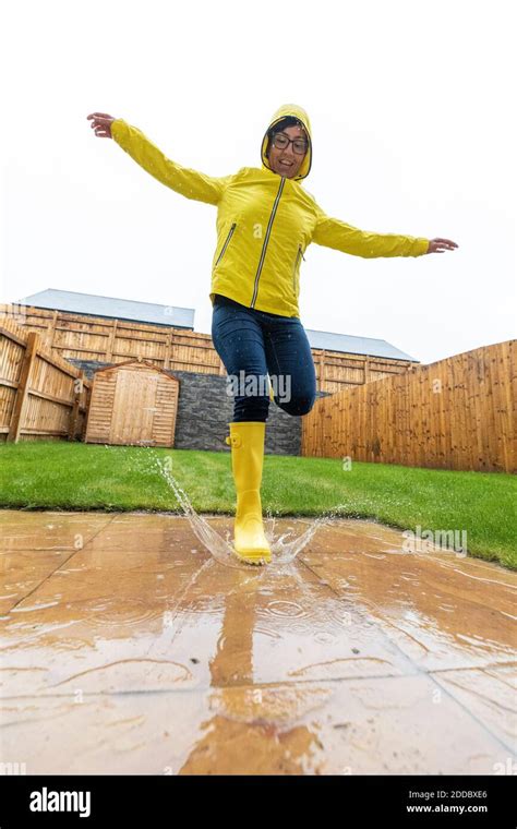 Woman jumping in water puddle during rainy season Stock Photo - Alamy