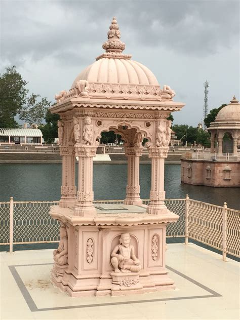 a white gazebo sitting on the side of a river next to a fenced in area