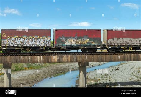 Street graffiti on containers on a cargo train over a blue background ...