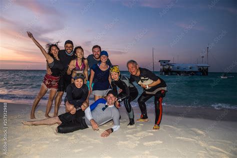 Friends posing for portrait on beach at sunset Stock Photo | Adobe Stock