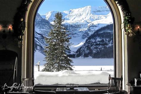 view of wintery lake louise from inside the fairmont chateau hotel restuaurant lounge