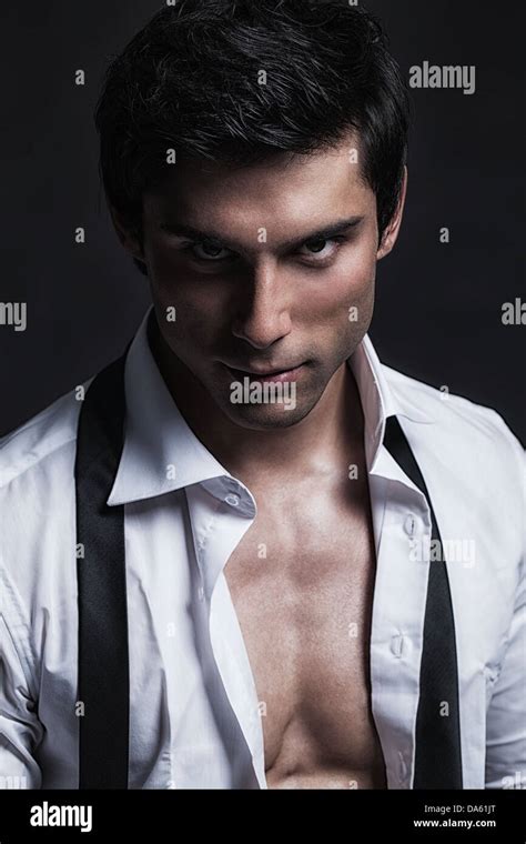 A handsome male model posing at a studio in front of a black background ...