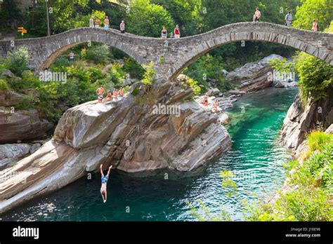 View Of a Diver Leaping From Ponte Dei Salti Bridge Over River At Valle Verzasca, Switzerland ...