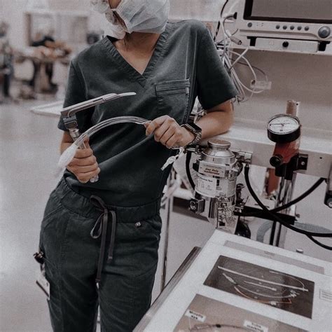 a woman in scrubs is holding a wrench and looking at the camera while wearing a surgical mask