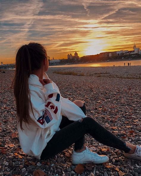 Download A Girl Sitting On The Beach At Sunset | Wallpapers.com