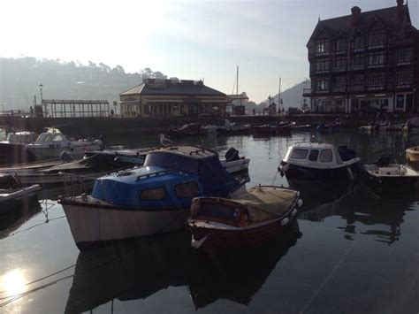 several small boats are docked in the water near some large buildings and houses on the shore