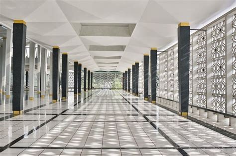 a long hallway with white and black columns on both sides, lined with glass partitions