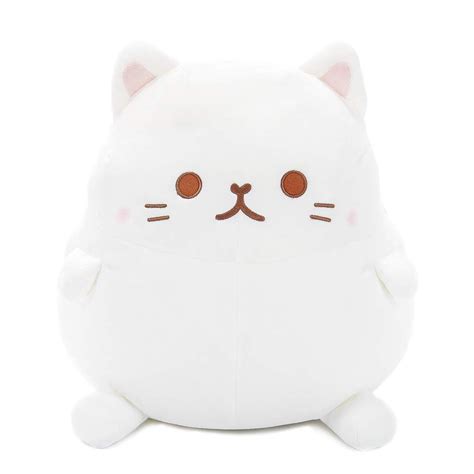 a white cat stuffed animal sitting on top of a white floor cushion with ...