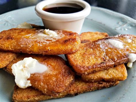 some french toast on a blue plate with butter and syrup in the middle ...