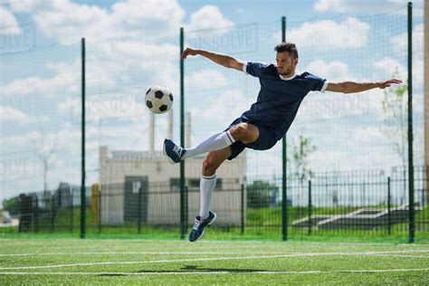 Athletic soccer player kicking ball on soccer pitch - Stock Photo - Dissolve