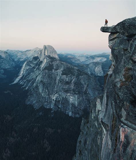 A fearless hiker is standing on an overhanging rock enjoying the view ...