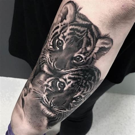 Black and grey tiger cubs tattoo on the forearm.