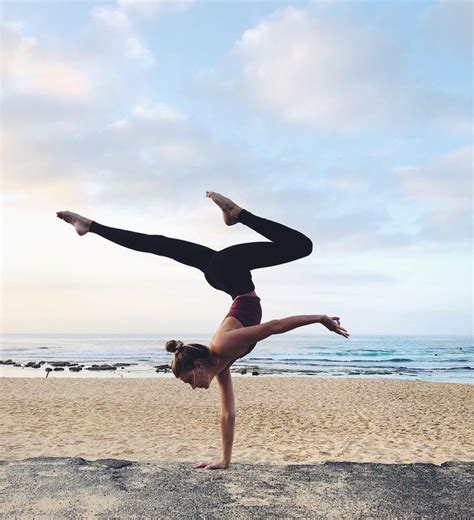 a woman doing a handstand on the beach with her feet in the air