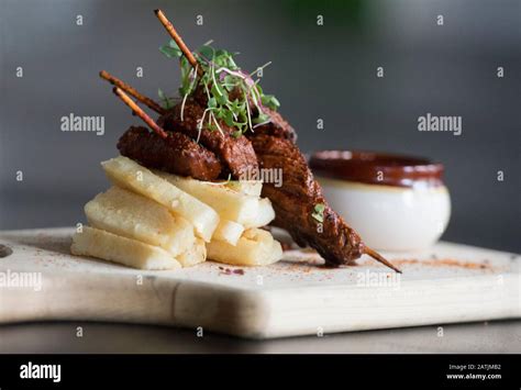 Anticucho Beef skewers with Yuka fries and tari sauce are shown on a table in a restaurant Stock ...