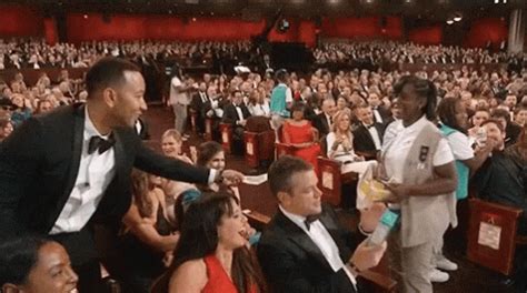 a man in a tuxedo is shaking hands with an audience