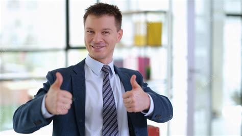 Premium Photo | Successful businessman in suit showing thumbs up in office