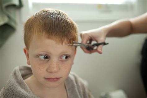 Caucasian mother giving son haircut stock photo