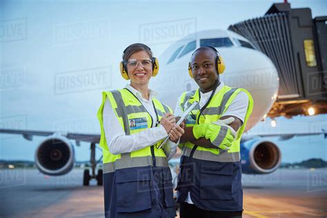 Portrait confident air traffic control ground crew workers near airplane on airport tarmac ...