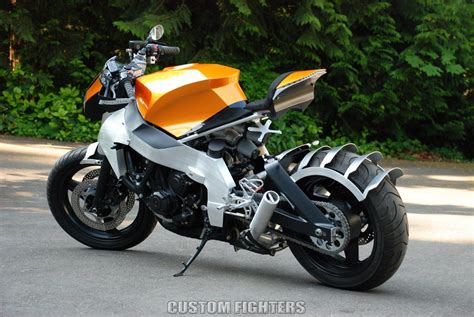 an orange and silver motorcycle parked on the side of a road in front of some trees