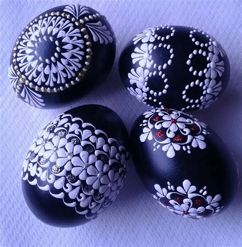 four black and white painted eggs with designs on them