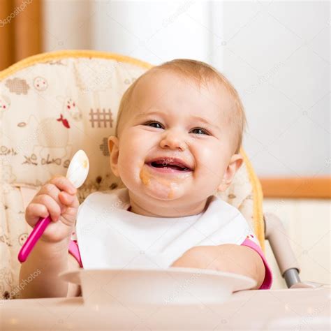 Smiling baby eating food on kitchen — Stock Photo © oksun70 #39704261