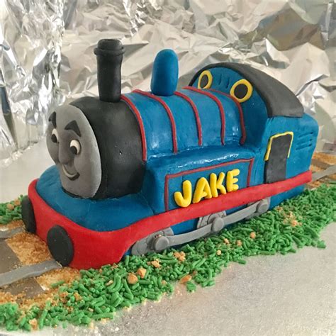 a thomas the tank engine cake is on top of some green grass and tin foil