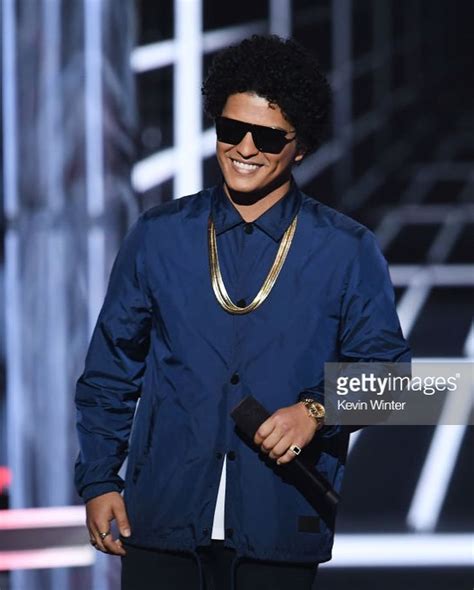 an image of a man that is on stage wearing sunglasses and holding a ...