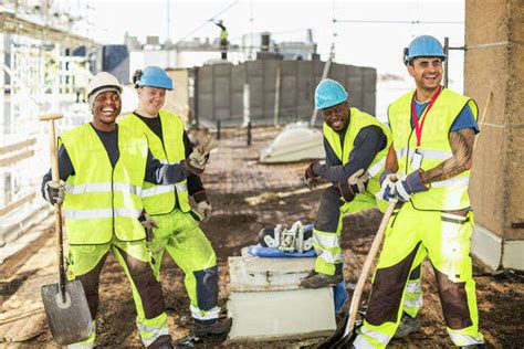 Happy construction workers at construction site - Stock Photo - Dissolve