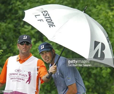 Caddie Lance Bennett holds an umbrella for Matt Kuchar on the 8th ...